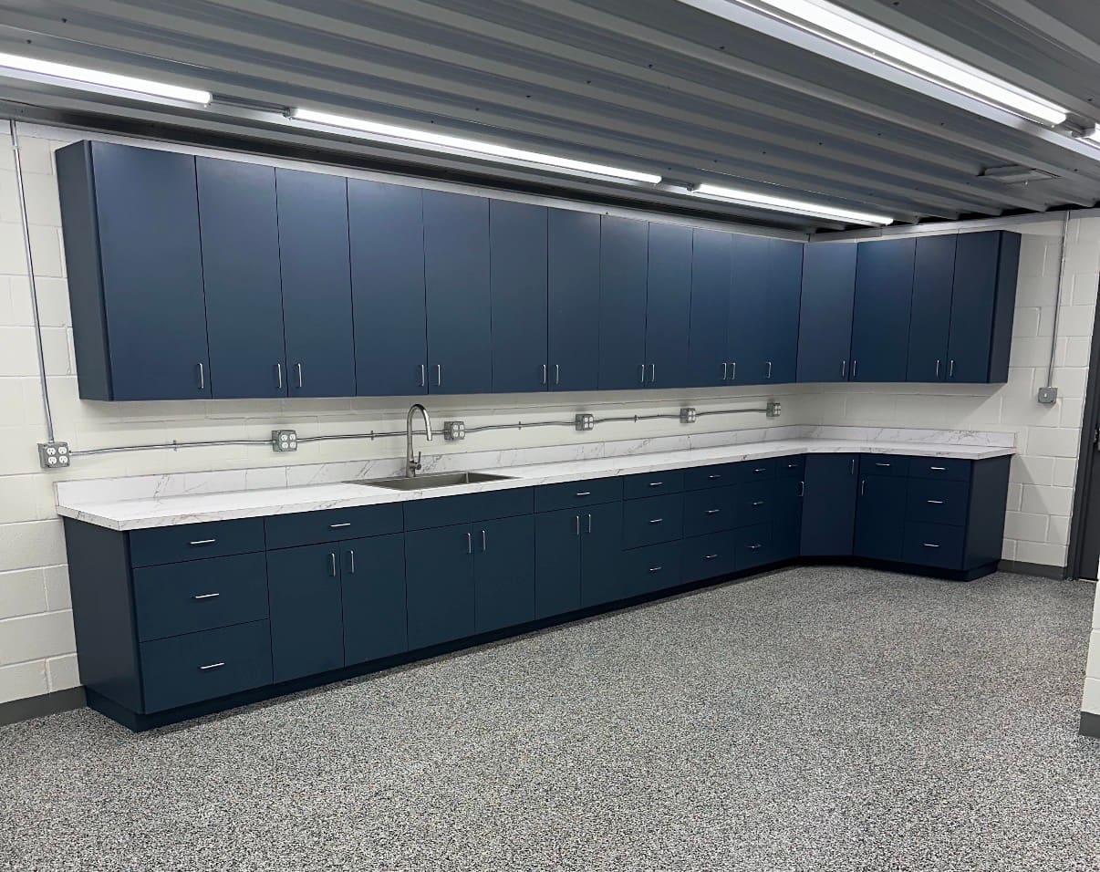 Navy upper and lower casework with white solid surface countertops and stainless sink