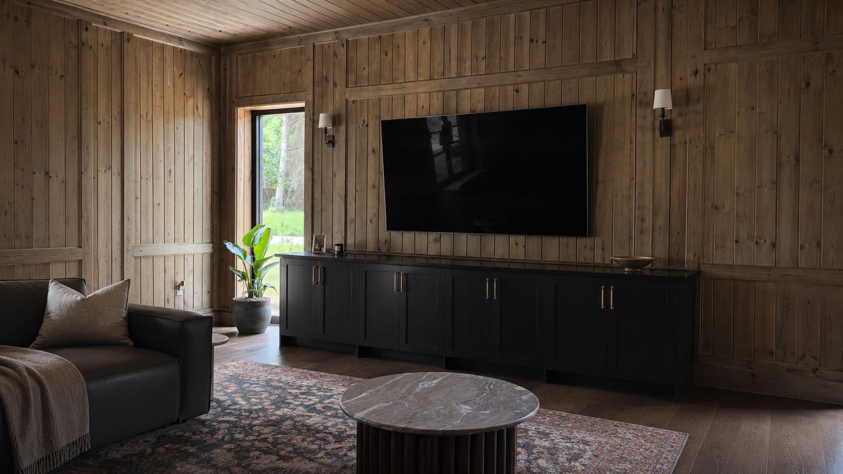 Wide view of the renovated living room with wood paneling and black media built-in