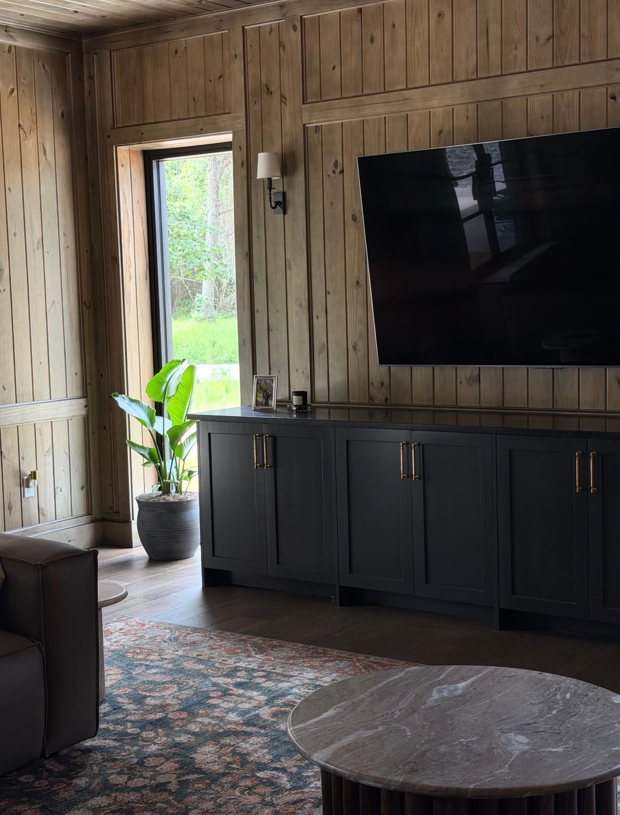 Detail view of the custom black media cabinet, wood paneling, and entry