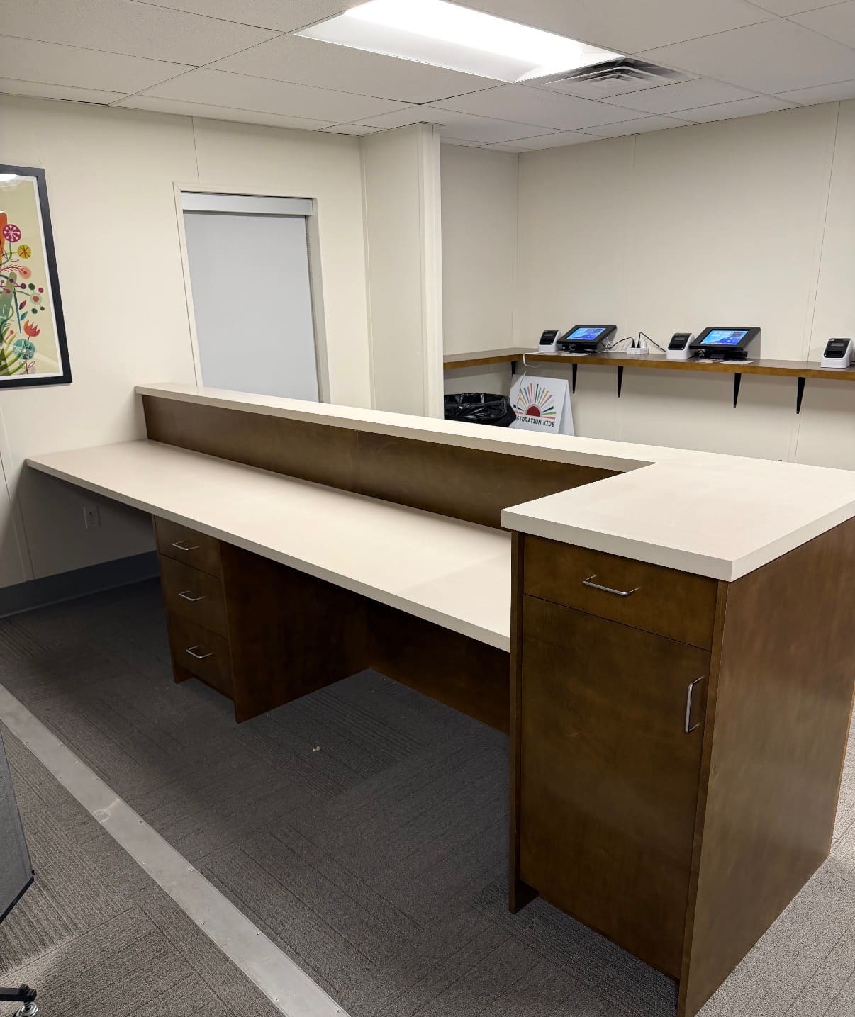 Custom wood reception and check-in desk with white solid surface countertops